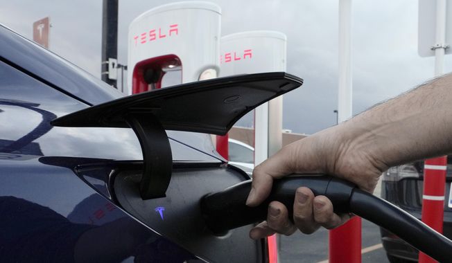 A motorist charges his electric vehicle at a Tesla Supercharger station in Detroit, Wednesday, Nov. 16, 2022. New Jersey residents looking to buy or lease an electric vehicle won’t be able to get a government rebate — at least temporarily — because the state program has been so popular that it&#x27;s already running out of money, officials said, Tuesday, April 18, 2023. (AP Photo/Paul Sancya, File)
