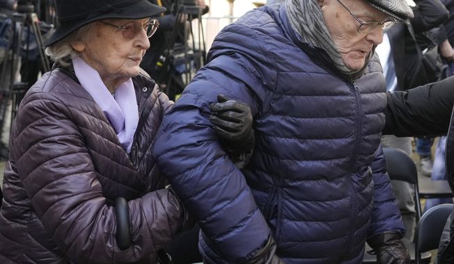 Anna Stupnicka-Bando, left, a Polish Christian honored for saving Jews, walks with Waclaw Kornblum, right, a Polish Holocaust survivor, at a ceremony for the burial of a &quot;time capsule&quot; on the grounds of the Warsaw Ghetto Museum in Warsaw, Poland, on Tuesday April 18, 2023. The time capsule contains memorabilia and a message to future generations. It was buried on the grounds of a former children&#x27;s hospital, a building that will house the Warsaw Ghetto Museum, which is scheduled to open in three years. Tuesday&#x27;s ceremony comes on the eve of the 80th anniversary of the Warsaw Ghetto Uprising, the largest single Jewish revolt against German forces during the Holocaust. (AP Photo/Czarek Sokolowski)