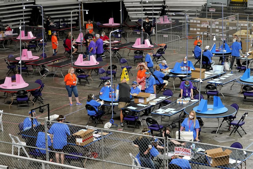 Contractors working for the Florida-based company Cyber Ninjas examine and recount 2020 general election ballots for Maricopa County, Ariz., at Veterans Memorial Coliseum in Phoenix on May 6, 2021. In late March 2023, the Arizona Senate agreed to pay $150,000 to American Oversight, which promotes government transparency, to settle a public records lawsuit over emails, texts and other records involving a partisan audit of the 2020 election. (AP Photo/Matt York, Pool,File)