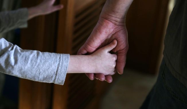 An autistic boy holds the hand of his adoptive father as they prepare to leave for a family outing from their home in Springfield, Mass., on Saturday, Dec. 12, 2015. (AP Photo/Charles Krupa, File)
