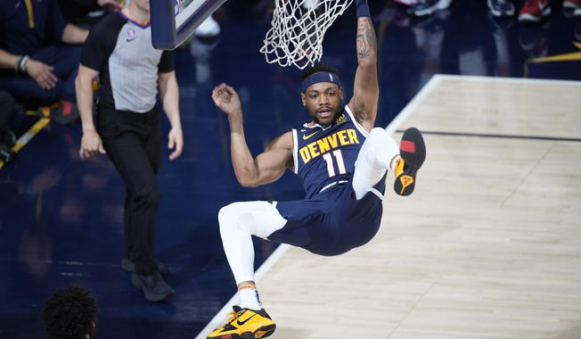 Denver Nuggets forward Bruce Brown hangs from the rim after a dunk against the Minnesota Timberwolves during the first half of Game 2 in an NBA basketball first-round playoff series Wednesday, April 19, 2023, in Denver. (AP Photo/David Zalubowski)