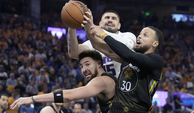 Sacramento Kings center Alex Len, top, reaches for the ball over Golden State Warriors guard Klay Thompson, left, and guard Stephen Curry (30) during the first half of Game 3 in the first round of the NBA basketball playoffs in San Francisco, Thursday, April 20, 2023. (AP Photo/Jeff Chiu)