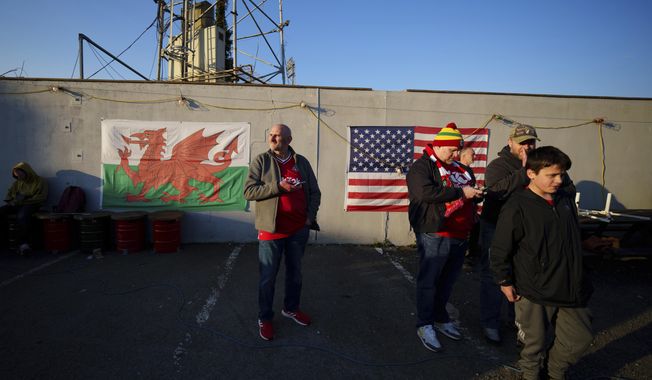 Supporters gather next to walls adorned with the Welsh and U.S. flags outside Wrexham&#x27;s Racecourse Ground before the National League soccer match between Wrexham and Yeovil Town in Wrexham, Wales, Tuesday, April 18, 2023. (AP Photo/Jon Super)