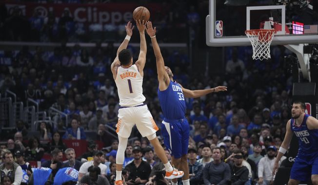 Los Angeles Clippers forward Nicolas Batum (33) defends against Phoenix Suns guard Devin Booker (1) during the first half of Game 3 of a first-round NBA basketball playoff series in Los Angeles, Thursday, April 20, 2023. (AP Photo/Ashley Landis)