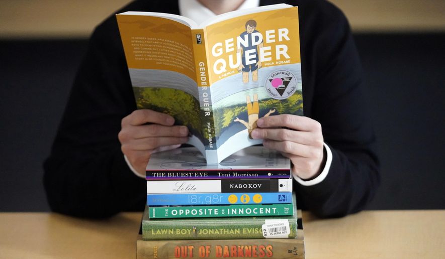 Amanda Darrow, director of youth, family and education programs at the Utah Pride Center, poses with books that have been the subject of complaints from parents on Dec. 16, 2021, in Salt Lake City. With legislators in Florida barring even the mention of being gay in classrooms and similar restrictions being considered in other states, books with LGBTQ+ themes remain the most likely targets of bans or attempted bans at public schools and libraries around the country, according to a new report Monday, April 24, 2023. Maia Kobabe’s graphic memoir “Gender Queer,” was the most “challenged” book of 2022, the second consecutive year it has topped the list. (AP Photo/Rick Bowmer) **FILE**