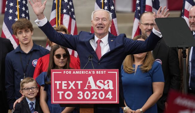 Former Arkansas Gov. Asa Hutchinson is surrounded by family members after formally announcing his Republican campaign for president, Wednesday, April 26, 2023, in Bentonville, Ark. (AP Photo/Sue Ogrocki)