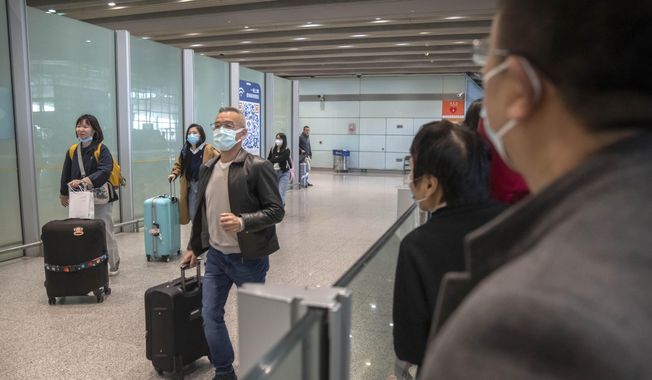 Travelers wearing face masks walk through the international arrivals area at Beijing Capital International Airport in Beijing, on March 15, 2023. Travelers entering China will no longer need to provide a negative PCR test result starting from Saturday, April 29, 2023, in another easing of China&#x27;s &quot;zero-COVID&quot; policies. (AP Photo/Mark Schiefelbein)