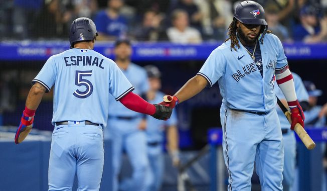 Toronto Blue Jays&#x27; Santiago Espinal (5) celebrates with teammate Vladimir Guerrero Jr. (27) after scoring a run against the Chicago White Sox during the third inning of a baseball game in Toronto, Wednesday, April 26, 2023. (Andrew Lahodynskyj/The Canadian Press via AP)