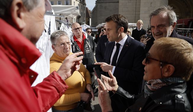 French President Emmanuel Macron, center, greets people as he visits the Dole market before a visit to the Chateau de Joux, for a ceremony marking the 175th anniversary of the abolition of slavery in France,Thursday, April 27 April 2023 in Dole, eastern France. (Christophe Petit Tesson, Pool via AP)