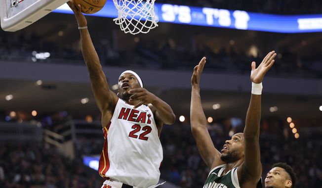 Miami Heat forward Jimmy Butler, left, shoots next to Milwaukee Bucks forward Khris Middleton during the first half of Game 5 in a first-round NBA basketball playoff series Wednesday, April 26, 2023, in Milwaukee. (AP Photo/Jeffrey Phelps)