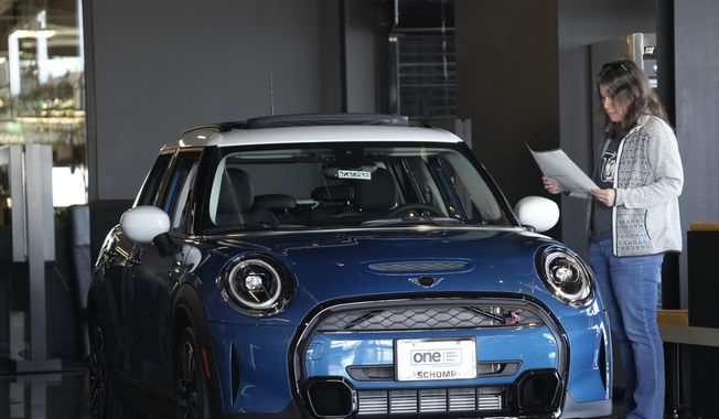 A potential buyer looks over a 2023 Cooper S sedan on the floor of a Mini dealership Friday, Feb. 17, 2023, in Highlands Ranch, Colo. On Friday, the Commerce Department issues its March report on consumer spending. (AP Photo/David Zalubowski, File)