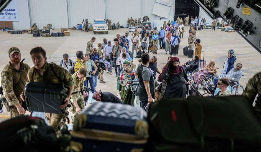 In this photo provided by the UK Ministry of Defence, British Nationals prepare to be evacuated onto a RAF aircraft at Wadi Seidna Air Base, in Sudan, Thursday, April 27, 2023. (PO Phot Arron Hoare/UK Ministry of Defence via AP)