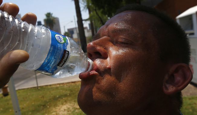 In this June 19, 2017 file photo Steve Smith takes a drink of water as he tries to keep hydrated and stay cool as temperatures climb to near-record highs, in Phoenix. As heat waves fueled by climate change arrive earlier, grow more intense and last longer, people over 60 who are more vulnerable to high temperatures are increasingly at risk of dying from heat-related causes. (AP Photo/Ross D. Franklin, File)