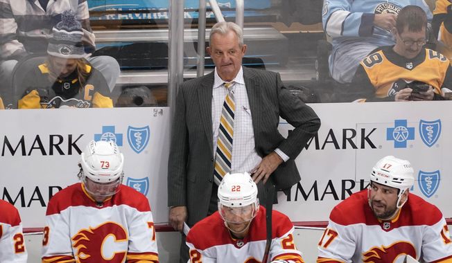 Calgary Flames head coach Darryl Sutter stands behind his bench during the third period of an NHL hockey game against the Pittsburgh Penguins in Pittsburgh, Wednesday, Nov. 23, 2022. The Calgary Flames fired head coach Darryl Sutter on Monday, May 1, 2023, the latest major change at the NHL club after a disappointing season.(AP Photo/Gene J. Puskar, File) **FILE**