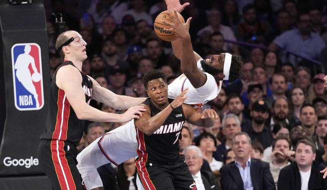 Miami Heat center Cody Zeller, left, watches New York Knicks center Mitchell Robinson fall over Miami Heat guard Kyle Lowry (7) while fighting for a rebound in the first half of Game 2 in the NBA basketball Eastern Conference semifinals playoff series, Tuesday, May 2, 2023, at Madison Square Garden in New York. (AP Photo/Mary Altaffer)