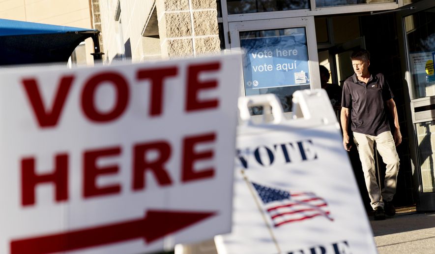 Signs point to the entrance on the last day of early voting before the midterm election as a man walks out of a polling site in Cranston, R.I., on Nov. 7, 2022. Almost half of all voters in the 2022 midterm elections cast their ballots before Election Day either by mail or through early voting, with Asian and Hispanic voters leading the way, new data from the U.S. Census Bureau released Tuesday, May 2, 2023, shows, even as Republican-led states have tightened rules on voting by mail. (AP Photo/David Goldman, File)