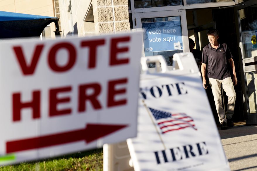 Signs point to the entrance on the last day of early voting before the midterm election as a man walks out of a polling site in Cranston, R.I., on Nov. 7, 2022. Almost half of all voters in the 2022 midterm elections cast their ballots before Election Day either by mail or through early voting, with Asian and Hispanic voters leading the way, new data from the U.S. Census Bureau released Tuesday, May 2, 2023, shows, even as Republican-led states have tightened rules on voting by mail. (AP Photo/David Goldman, File)