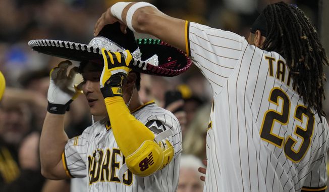 San Diego Padres&#x27; Fernando Tatis Jr. (23) puts a sombrero on teammate Ha-Seong Kim after Kim hit a three-run home run during the fifth inning of a baseball game against the Cincinnati Reds, Monday, May 1, 2023, in San Diego. (AP Photo/Gregory Bull)