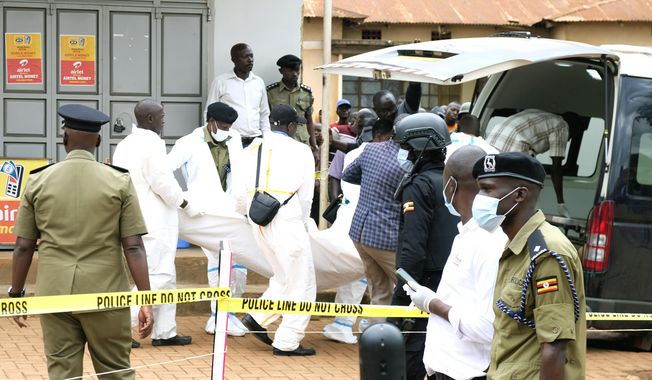 The body of a bodyguard is put into an ambulance by Ugandan medical staff in Kyanja village, Kampala, Tuesday May 2, 2023. A bodyguard shot and killed a government minister in Uganda early Tuesday in an apparent private dispute, according to the army and local media. The attacker, who has not been publicly identified, then turned the gun on himself, according to state broadcaster UBC and others. (AP Photo/Ajar Nalwadda)