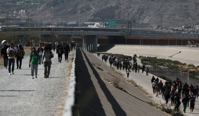 Migrants walk along the Mexico-U.S. border in Ciudad Juarez, Mexico, Wednesday, March 29, 2023, a day after dozens of migrants died in a fire at a migrant detention center in Ciudad Juarez. (AP Photo/Christian Chavez)