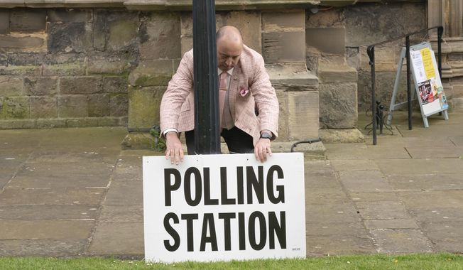 A polling station sign is adjusted outside the polling station in Bridlington, England, Thursday, May 4, 2023. Millions of people in England are voting Thursday in local elections, the first test of electoral opinion since Prime Minister Rishi Sunak took over a fractious and exhausted Conservative Party six months ago. (Danny Lawson/PA via AP)