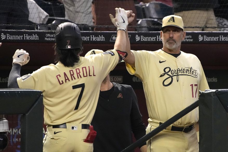 Arizona Diamondbacks' Corbin Carroll gets a high five from manager Torey Lovullo (17) after hitting a solo home run against the Washington Nationals in the third inning during a baseball game, Friday, May 5, 2023, in Phoenix. (AP Photo/Rick Scuteri)