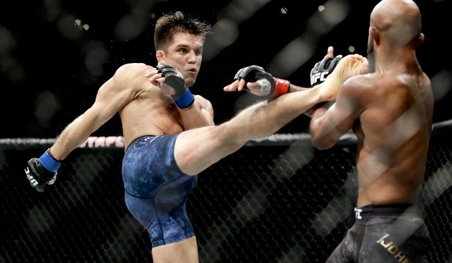 In this Aug. 4, 2018, file photo, Henry Cejudo, left, kicks Demetrious Johnson during their UFC flyweight title mixed martial arts bout at UFC 227 in Los Angeles. Former two-division world champion Henry Cejudo fights for the bantamweight title bout against reigning champion Aljamain Sterling. The are the main event of UFC 288 on Saturday at the Prudential Center in Newark, N.J. (AP Photo/Chris Carlson, File)
