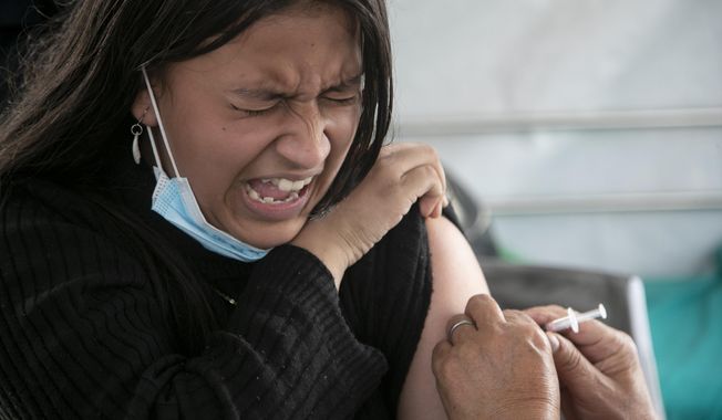 A girl reacts as she receives a shot of the Pfizer-BioNTech vaccine for COVID-19 in Kathmandu, Nepal, Tuesday, Nov. 23, 2021. Children above the age of 12 are now receiving the vaccine in Nepal. The World Health Organization downgraded its assessment of the coronavirus pandemic on Friday, May 5, 2023, saying it no longer qualifies as a global emergency. (AP Photo/Niranjan Shrestha, File)