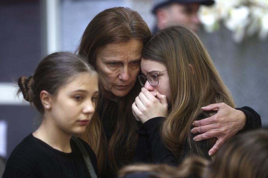 Woman comforts a child after signing the book of condolences in front of Vladimir Ribnikar school, two days after a 13-year-old boy used his father's guns to kill eight fellow students and a guard in Belgrade, Serbia, Friday, May 5, 2023. The bloodshed sent shockwaves through a Balkan nation scarred by wars, but unused to mass murders. (AP Photo/Armin Durgut)