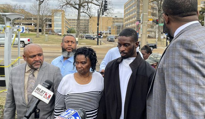 Michael Jenkins, second from right, stand with his mother, Mary Jenkins, center, and their attorneys at a news conference on Feb. 15. 2023, in Jackson, Miss., following his release from the hospital three weeks after being shot by sheriff&#x27;s deputies. Mississippi deputies tried to assault two Black men with a sex toy and forced them to shower together during an hours-long interrogation in which Jenkins was shot in the mouth, the men’s attorney said in a letter to the U.S. Justice Department Monday, May 8, urging that civil rights charges be brought. (AP Photo/Michael Goldberg, File)