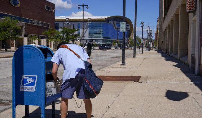 A postal worker empties a box near the Fiserv Forum on Aug. 18, 2020, in Milwaukee. Postal carriers have more worries than snow, rain or the gloom of night keeping them from their appointed rounds. These days, they&#x27;re increasingly being robbed, often at gunpoint, from Maine to California. (AP Photo/Morry Gash, File)