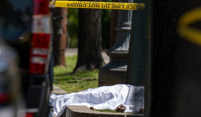 A victim lies under a sheet as Metropolitan Police Department officers investigate the shooting scene in front of Stewart Funeral Home, Tuesday, April 11, 2023, in Washington. Police say a man was killed and three others were critically injured in a shooting outside of a funeral for a homicide victim in the nation鈥檚 capital. (AP Photo/Alex Brandon) **FILE**