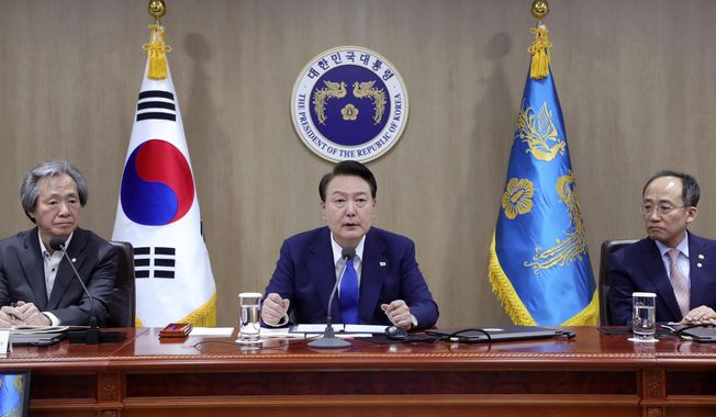 South Korean President Yoon Suk Yeol, center, speaks during a meeting of the Central Disaster and Safety Countermeasures Headquarters about measures to deal with the coronavirus pandemic at the presidential office in Seoul, South Korea, Thursday, May 11, 2023. South Korea will drop its COVID-19 quarantine requirements and end testing recommendations for international arrivals starting next month after the World Health Organization declared the end of the global health emergency. (Yonhap via AP)