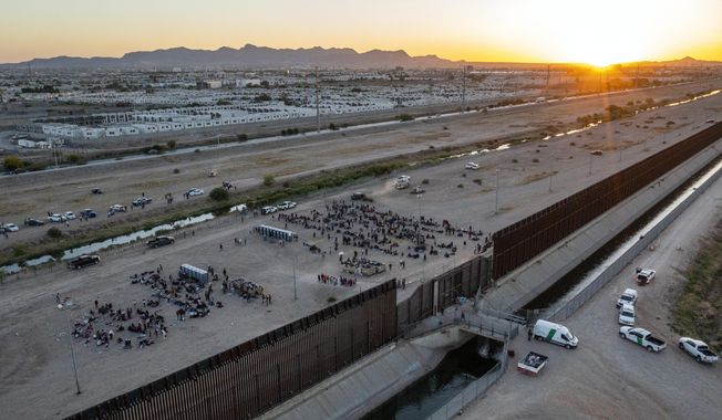 As the sun sets, migrants wait outside a gate in the border fence to enter into El Paso, Texas, to be processed by the Border Patrol, Thursday, May 11, 2023. (AP Photo/Andres Leighton) ** FILE **