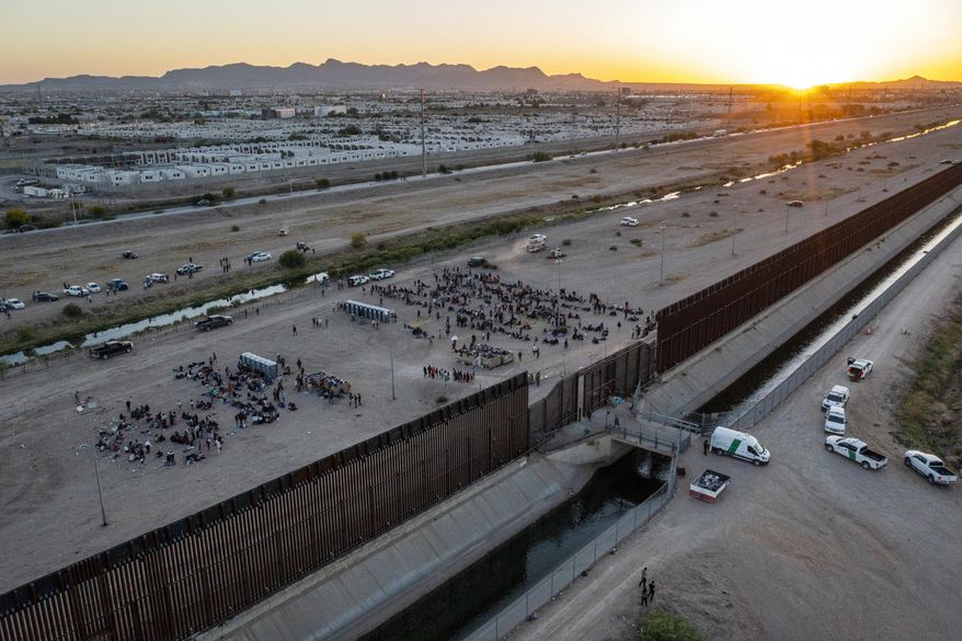As the sun sets, migrants wait outside a gate in the border fence to enter into El Paso, Texas, to be processed by the Border Patrol, Thursday, May 11, 2023. (AP Photo/Andres Leighton) ** FILE **