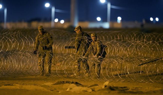 Texas National Guard soldiers install new rows of barbed-wire near a gate at the border fence in El Paso, Texas, in the early hours of Thursday, May 11, 2023. Migrants rushed across the border hours before pandemic-related asylum restrictions were to expire Thursday, fearing that new policies would make it far more difficult to gain entry into the United States. (AP Photo/Andres Leighton)