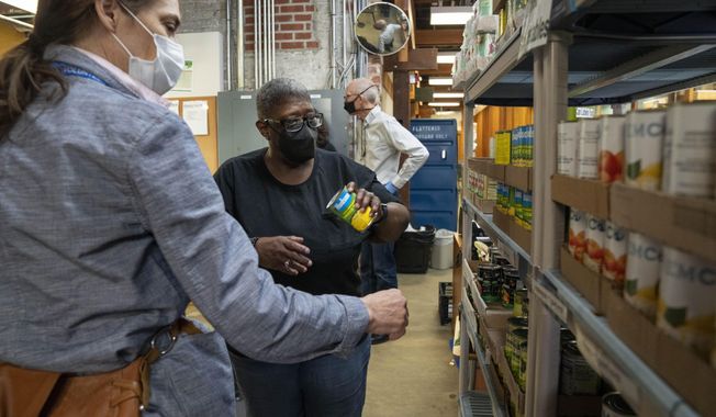 Helena Smith, center, of Washington, chooses a food item while shopping at Bread for the City, Wednesday, May 10, 2023, a food pantry in Washington. The formal end of the national Public Health Emergency on Thursday marks the end of several U.S. pandemic-era emergency support program, from extra food assistance to automatic enrollment in Medicaid. &quot;I like this a lot because they give us a variety of fruit,&quot; says Smith, &quot;instead of just cans.&quot; (AP Photo/Jacquelyn Martin)
