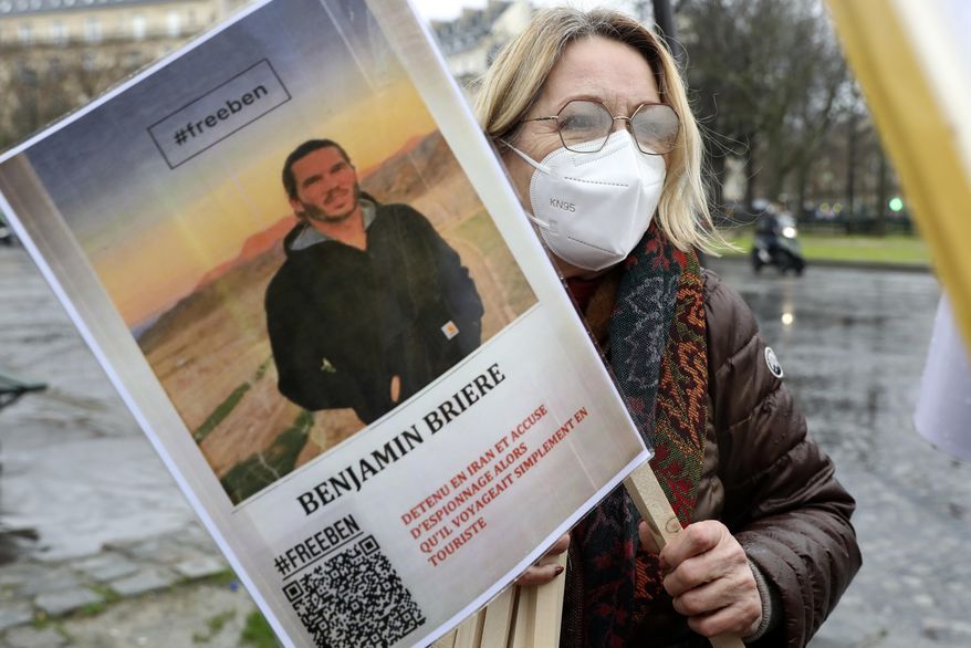 A woman holds a photo of Benjamin Briere during a rally in Paris, France, Saturday, Jan. 8, 2022. Two French citizens imprisoned in Iran have been freed, France's foreign minister said Friday. Benjamin Briere and Bernard Phelan, who both had been held in a prison in Mashad, in northwest Iran, were heading to Paris, a statement from Foreign Minister Catherine Colonna said. (AP Photo/Adrienne Surprenant, File)