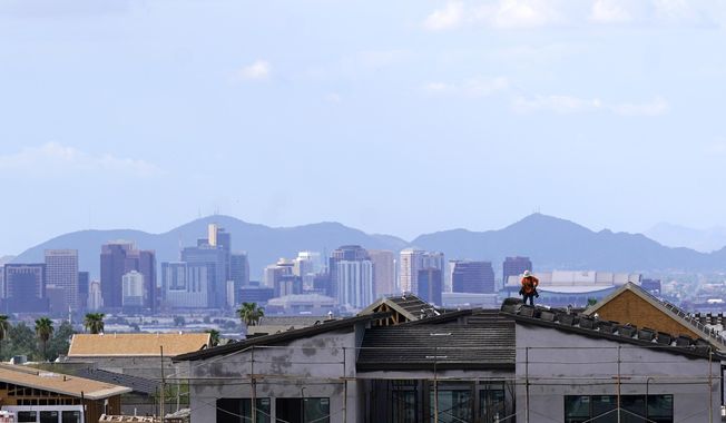 In this Aug. 12, 2021, file photo with the downtown skyline in the background, a roofer works on a new home being built in a new housing development as expansive urban sprawl continues in Phoenix. Some of the largest U.S. cities challenging their 2020 census numbers aren&#x27;t getting the results they hoped for from the U.S. Census Bureau. (AP Photo/Ross D. Franklin) **FILE**