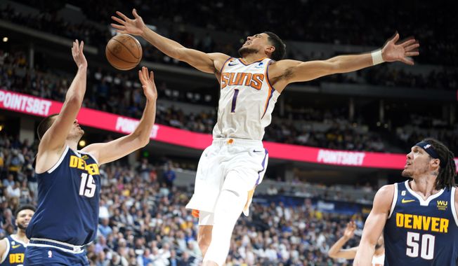 Phoenix Suns guard Devin Booker, center, loses control of the ball while driving to the rim between Denver Nuggets center Nikola Jokic, left, and forward Aaron Gordon in the second half of Game 2 of an NBA second-round playoff series Monday, May 1, 2023, in Denver. (AP Photo/David Zalubowski)