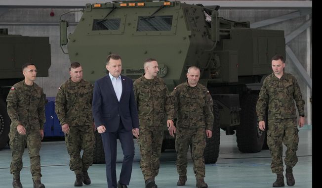Poland&#x27;s Defense Minister Mariusz Blaszczak, center, walks during ceremony after receiving its first shipment of U.S.-made HIMARS rocket launchers, at an air base in Warsaw, Poland, on Monday, 15 May 2023. Poland has received its first shipment of U.S.-made HIMARS rocket launchers, part of an upgrade of its defenses amid security concerns due to the war in neighboring Ukraine. (AP Photo/Czarek Sokolowski)