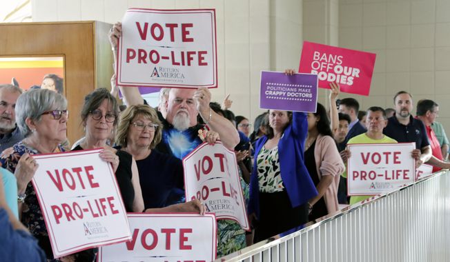 Protesters on both sides of the issue hold signs, Tuesday, May 16, 2023, in Raleigh, N.C., as they wait to enter the Senate gallery as North Carolina legislators debate on whether to override Democratic Gov. Roy Cooper&#x27;s veto of a bill that would change the state&#x27;s ban on nearly all abortions from those after 20 weeks of pregnancy to those after 12 weeks of pregnancy. Both the Senate and House had to complete successful override votes for the measure to be enacted into law. (AP Photo/Chris Seward)