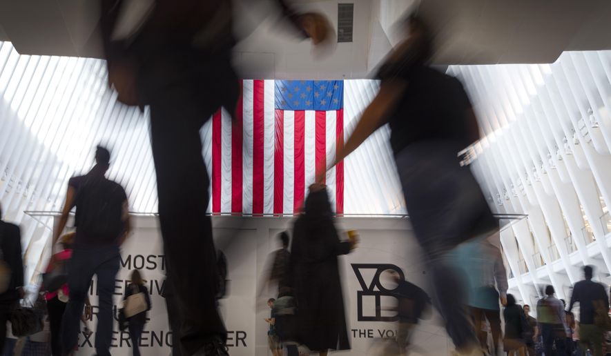 People walk past an American flag inside the Oculus, part of the World Trade Center transportation hub, at the start of a work day in New York, Sept. 11, 2019. American lore is full of tales of a nation built on the foundations of individualism. In reality, loneliness in America can be deadly. In May 2023, the U.S. surgeon general declared it an epidemic, saying that it takes as deadly a toll as smoking. (AP Photo/Wong Maye-E, File)