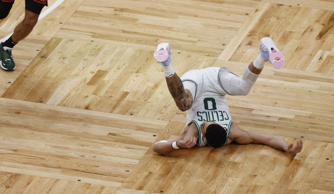 Boston Celtics forward Jayson Tatum (0) falls to the court in the first half of Game 1 of the NBA basketball Eastern Conference finals playoff series against the Miami Heat in Boston, Wednesday, May 17, 2023. (AP Photo/Michael Dwyer)