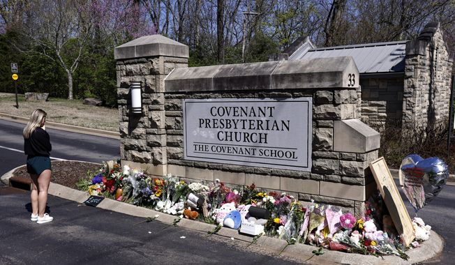 A woman pauses as she visits a memorial at the entrance to The Covenant School, March 29, 2023, in Nashville, Tenn. A group of Tennessee parents whose children attend The Covenant School, where a deadly shooting in March took the lives of three 9-year-olds and three adults, filed a motion on Wednesday, May 17, seeking to keep the shooter&#x27;s writings from being released to the public. (AP Photo/Wade Payne, File)