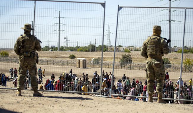 Migrants wait in line adjacent to the border fence under the watch of the Texas National Guard to enter into El Paso, Texas, Wednesday, May 10, 2023. U.S. authorities say an 8-year-old girl died Wednesday, May 17, in Border Patrol custody, a rare occurrence that comes as the agency struggles with overcrowding. The Border Patrol had 28,717 people in custody on May 10, the day before pandemic-related asylum restrictions expired, which was double from two weeks earlier, according to a court filing. (AP Photo/Andres Leighton, File)