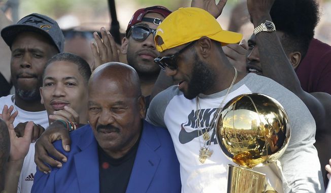 Former Cleveland Browns player Jim Brown, left, gets a hug from LeBron James, who holds the Larry O&#x27;Brien NBA championship trophy during a rally June 22, 2016, in Cleveland. “I hope every Black athlete takes the time to educate themselves about this incredible man and what he did to change all of our lives,” James posted shortly after Brown&#x27;s death. ”We all stand on your shoulders Jim Brown. If you grew up in Northeast Ohio and were Black, Jim Brown was a God.&quot; (AP Photo/Tony Dejak, File)
