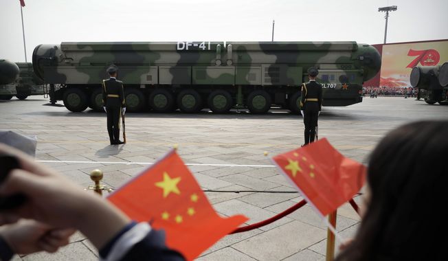 Spectators wave Chinese flags as military vehicles carrying DF-41 nuclear ballistic missiles roll during a parade to commemorate the 70th anniversary of the founding of Communist China in Beijing on Oct. 1, 2019. (AP Photo/Mark Schiefelbein, File)