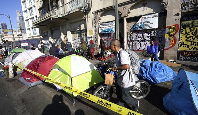 People line up along temporary tents to partake in a free Thanksgiving meal provided by the Union Rescue Mission as the Los Angeles Skid Row district annual feast hosts thousands of homeless and others in need, in downtown Los Angeles on Nov. 24, 2022. Democratic leaders in major U.S. cities are finding themselves politically squeezed when it comes to addressing homelessness. Some hope L.A.&#x27;s newly elected Mayor Karen Bass will make good on her campaign promise to move people out of tents and cardboard shanties and eventually into permanent housing. (AP Photo/Damian Dovarganes, File)