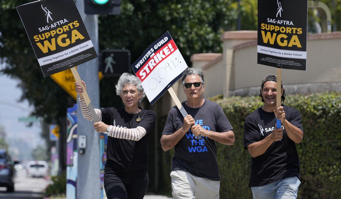 Actors Amy Aquino, left, and Michael Kajganich, right, join writer Steve Skrovan in a Writers Guild rally outside Warner Bros. Studios, Monday, May 22, 2023, in Burbank, Calif. (AP Photo/Chris Pizzello)